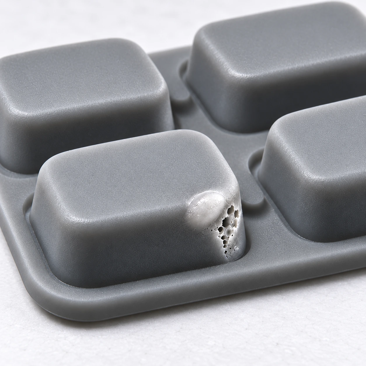 Illustrative reconstruction of a pale blister and opened porous bubble defect on a gray silicone keypad